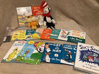 Full view of all Dr. Seuss books laid out with two plush toys, Cat in the Hat and The Lorax