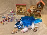 Top-down photo showing the full assortment of figurines, playsets, and plush pets including Calico Critters house and treehouse, Zhuzhu Pets airport terminal, and various small collectible toys.