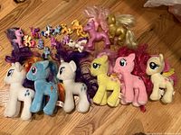 Overview photo showing all My Little Pony items together on floor, including mini figurines, plush ponies, and larger vintage ponies.