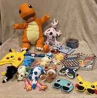 Full lot with giant plush Charmander, plush Eevee and evolutions, various figures, Pokémon-themed glasses, hat, tin, and books.