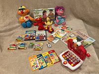 Full lot of Sesame Street items including plush toys, board game, laptop, books, and collectibles.