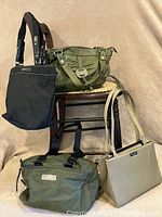 Photo showing four vegan bags including a black Kenneth Cole Reaction bag, a green Steve Madden shoulder bag, a beige Kate Spade shoulder bag satchel, and a green Relic vegan leather purse arranged on and around a wooden chair.