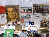 Wide angle photo showing most items together including Marine Corps League hat, Eddie Arnold portrait, magazines, and assorted small collectibles