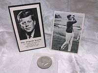 John F. Kennedy memoriam card with portrait, trading card showing JFK golfing, and 1974 Kennedy half dollar coin in plastic holder.