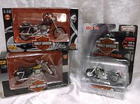 Three Maisto die cast Harley Davidson motorcycles, two 1:18 scale and one 1:24 scale in original packaging