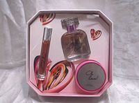 Photo of the Oh Love gift set showing perfume bottle, rollerball perfume, and body cream container inside heart-themed packaging.