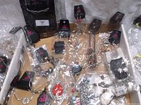Wide view showing assortment of Paparazzi jewelry pieces all wrapped in plastic packaging with black Paparazzi tags visible