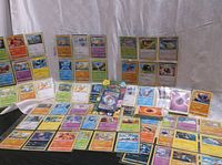 Wide view of multiple loose Pokemon cards laid out, sealed and sleeved cards included