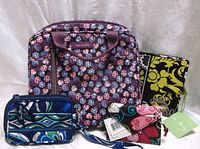 Photo showing all four items in the lot: Vera Bradley make up bag, small wallet, passport cover, and luggage tag.