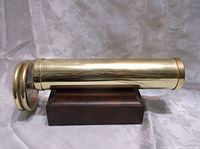 Side view of the brass kaleidoscope on its wooden stand showing overall length and finish.