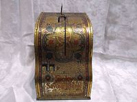 Front view of vintage Lucky Savings Bank showing curved shape, ornate patterns, numeric dials and the name.