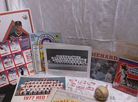 Photo showing collection of vintage Red Sox memorabilia including team photos, All Star Gallery magazine, and baseball with ephemera on basketball net background.