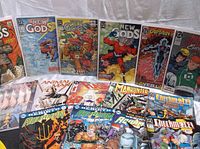 Photo showing a variety of DC comic books including New Gods, Animal Man, Checkmate, Captain Atom, Green Lantern, Manhunter, and Aquaman arranged side by side.