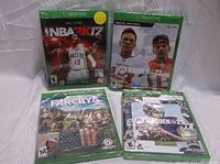Four sealed Xbox One game cases arranged on white cloth background: NBA 2K17, Madden NFL 22, Far Cry 5, Madden NFL 21.