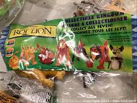 Close-up of a sealed Lion King character figure inside original branded plastic bag showing various characters and collectible info.