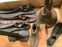 Photo showing multiple metal shoe lasts in different sizes with a round metal base stand behind.