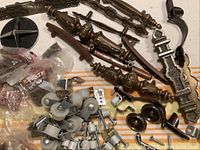 Overview of the hardware lot showing decorative brass drawer pulls, caster wheels, and various small metal hardware pieces, some in plastic bags.