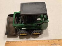 Side view of John Deere backhoe toy model showing rust on the bucket and overall condition.