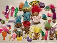 Overview of multiple troll dolls with colorful hair and toy accessories