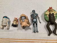 Wide view showing all five Star Wars figures including R2-D2, two Jar Jar Binks figures, a tan furry figure, and a silver droid figure.