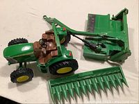 Photo of green and yellow John Deere toy tractor with brown seating and steering wheel with two separate green parts in front.