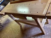Front-left perspective of bench showing top, dog holes, and legs