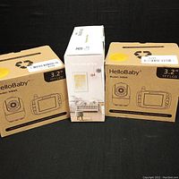 Three boxed baby monitors: two HelloBaby HB65 models with 3.2" TFT LCDs and one 3OIFun monitor in white packaging.