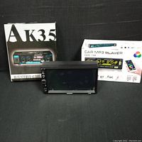 Two product boxes labeled AK35 and Car MP3 Player with a touchscreen device in front.