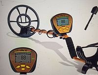 Metal detector fully assembled showing search coil, armrest, and digital display with control panel.