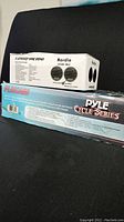Lot with Herdio HMS-60 marine speaker box and Pyle Cycle Series amplifier box side by side