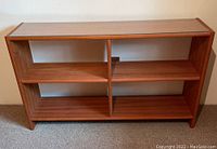 Front view of the low wood bookshelf showing three shelves divided by vertical supports, no back panel visible