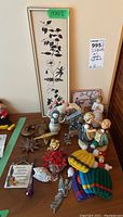 Overview of figurines, artificial flowers, framed print, and art tile on a wooden surface.