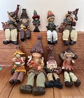 Full display of 9 elfin figurines arranged sitting on a wooden surface showing all different styles and sizes