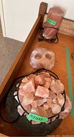 Photo showing the two electric Himalayan salt lamps; one on a ceramic platter with pink salt chunks in a metal basket, the other with a cylindrical pink salt lamp and a two-hole holder.