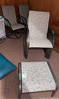 Six matching patio chairs including two rotating captain's chairs and one footstool, all with leaf-patterned fabric seats and black metal frames.