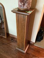 Full view of wood veneer pedestal showing vertical fluted design and square top and base.