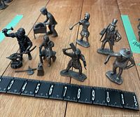 Full set of 7 Daalderop pewter figurines on wood floor with measuring tape showing approximate size around 4 inches tall.