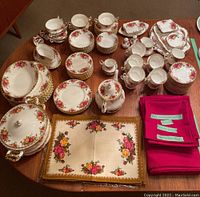 Overview of spread including plates, bowls, cups, saucers, teapot, consommé bowls, napkin rings, linens