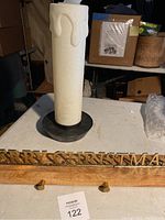 Photo showing battery operated candle light blow mold resembling a white candle with wax drips, mounted on a black base, with tip missing, and a wooden stocking holder with brass hooks and metallic 'Merry Christmas' letters in front