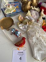 Overview of Christmas lot including angel ornament, red bird ornament, snowman figurine, brass candle holder, and partial view of battery operated train and Santa figure.