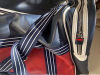 Close-up of Fila duffle bag shoulder straps and zipper with brand logo, showing material and color details.