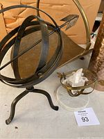 Photo showing brass armillary-style wood holder with arrow on a tripod stand alongside crystal cluster in brass and marble base