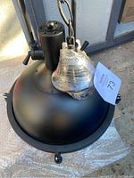 Matte black dome shade of ITFAD industrial pendant light with chain hanger and mounting hardware wrapped in plastic