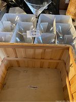 Full view of the wooden basket containing 11 martini glasses stored in cardboard dividers with one glass placed on top.