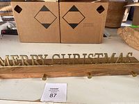 Photo showing the full length of the stocking holder with 'MERRY CHRISTMAS' metal letters on a wooden base and three metal hooks.