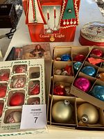 Vintage Christmas decoration box contents showing glass ornaments, CDs, felt door hangers, candle holders and tea tin