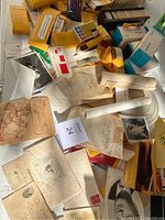 Overview of vintage photographs, postcards, yellow slide cases, paper rolls, and old envelopes spread on a surface.