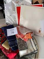 Overview of the collection showing several scarves in different patterns and some boxed kitchenware pieces.
