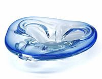 Blue art glass shallow bowl with smooth curved edges and clear polished base, shown on a white background