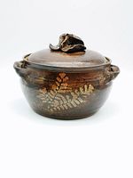 Front view of the bean pot showing leaf pattern and flower lid handle.